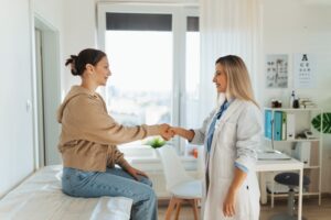 Teenage patient arriving at appointment with practitioner, shaking hands with female pediatrician, physician. Teen girl have consultation, first visit with gynecologist. Concept of preventive health care.